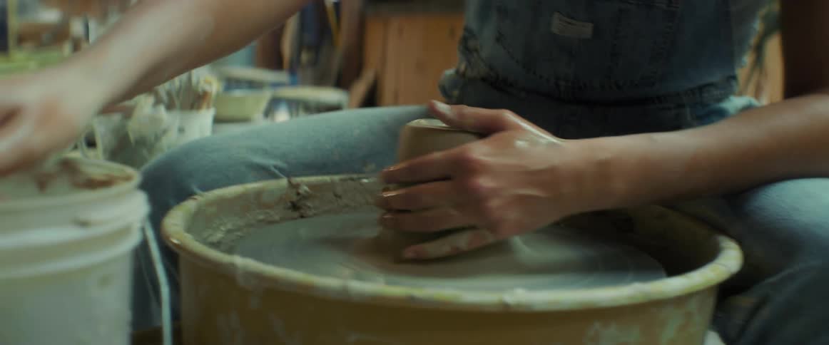 A potter sculpts clay using a potters wheel