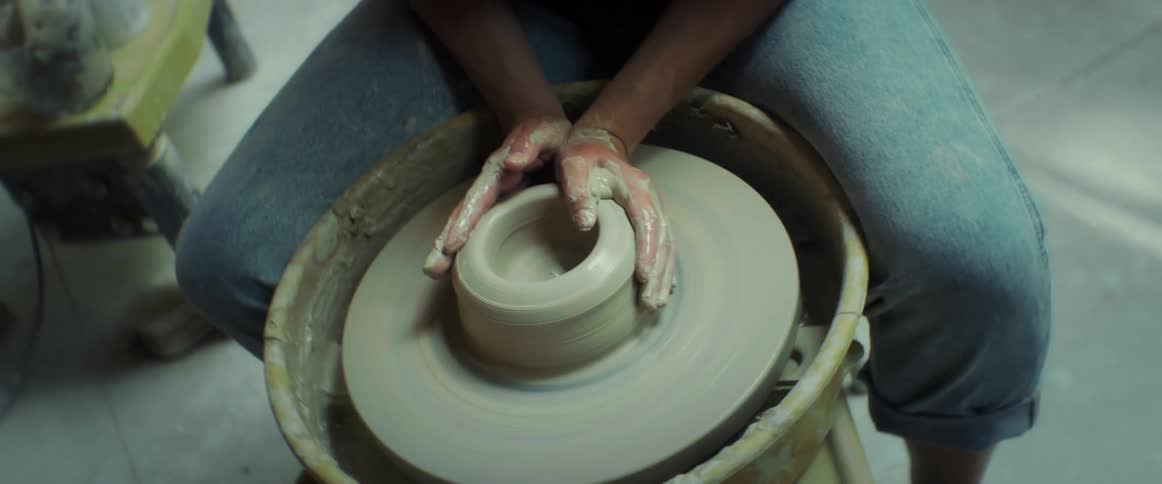 A woman is sculpting clay on the wheel