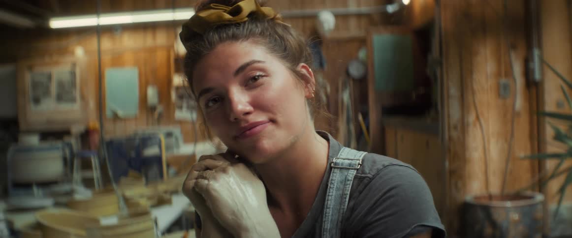 Portrait of a woman with a happy facial expression and her hands dirty with clay