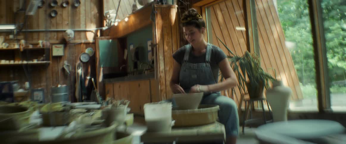 Woman sitting indoors making a clay pot