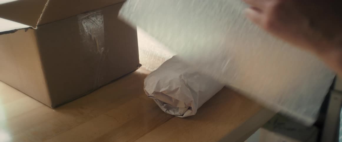 Close up of a person packing an object with paper and bubble wrap