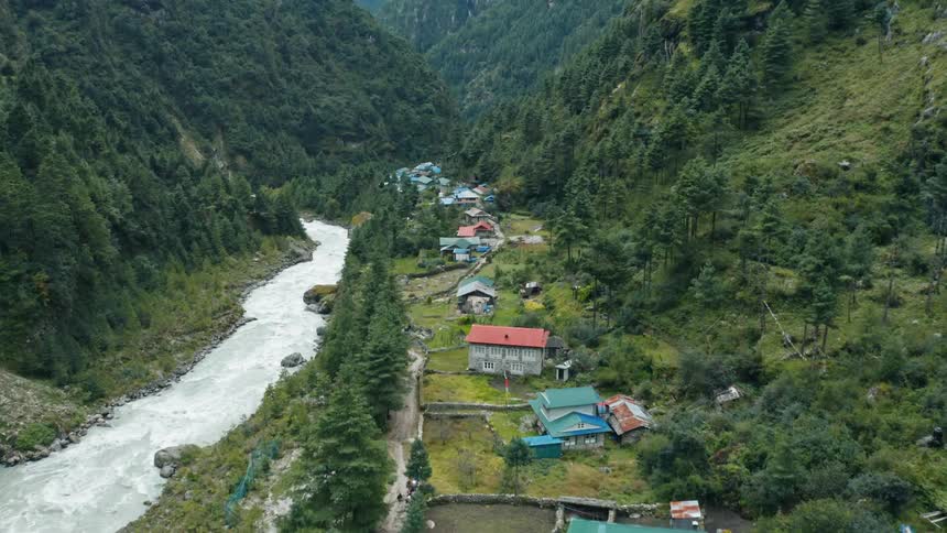 A winding river flows through a lush green valley near a small town