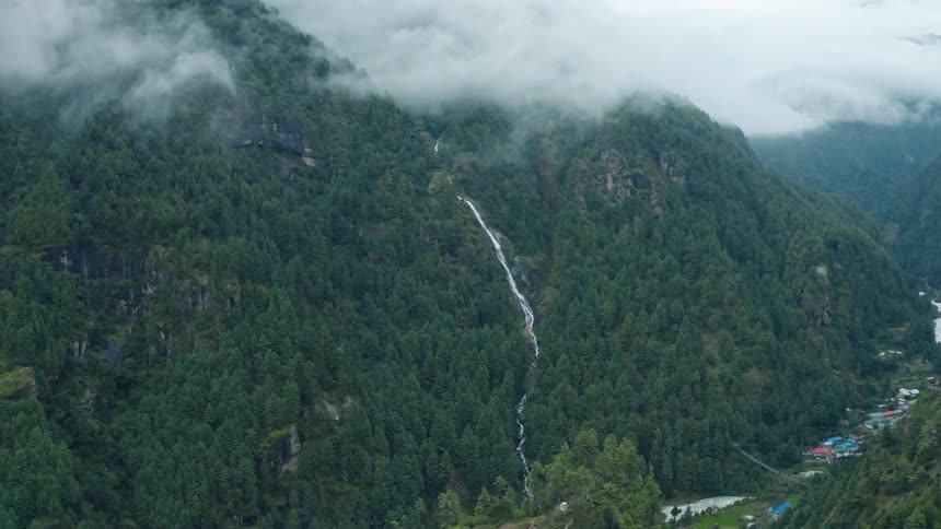Aerial aerial panorama of wooded mountains and a village in the background