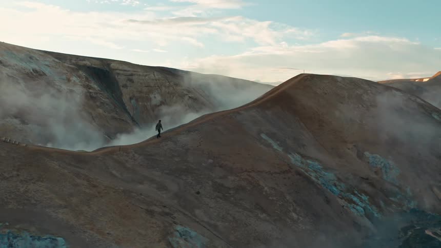 A man walks across the top of a mountain ridge
