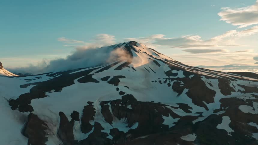 Clouds hover over the top of a mountain