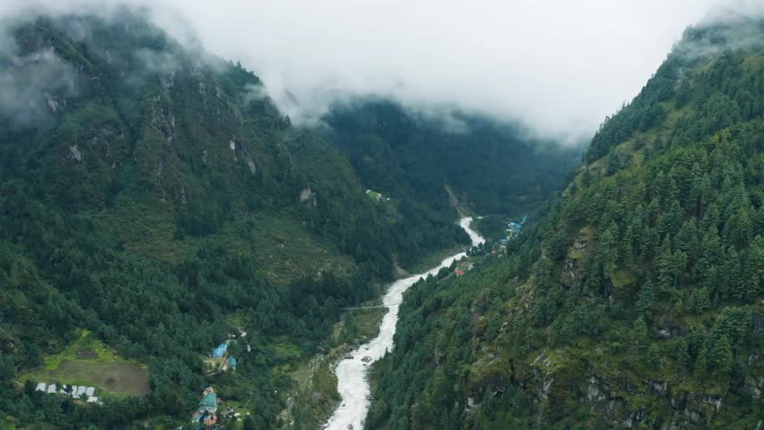 An aerial view of a winding river flowing through a lush green valley in the mountains