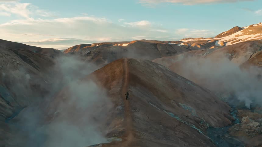 A person runs along a path on top of a mountain