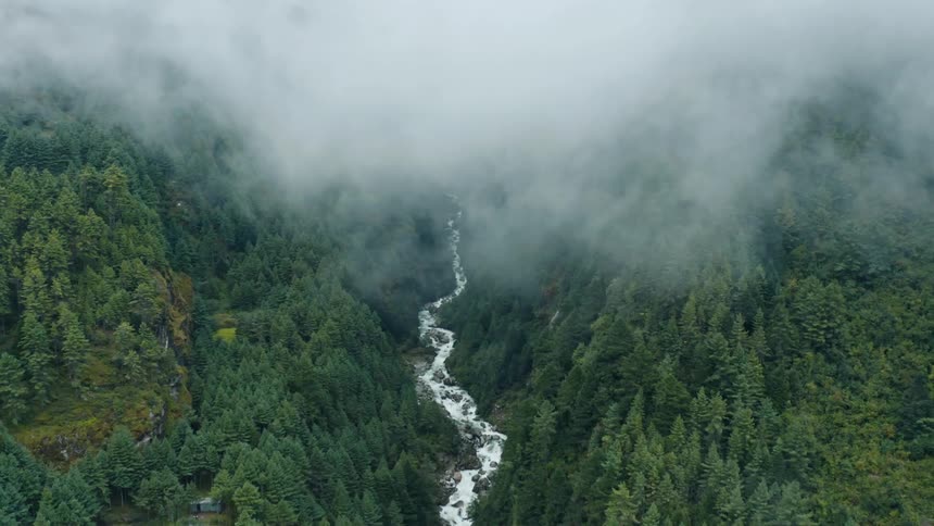 A river runs past a rural community and through a mountain valley