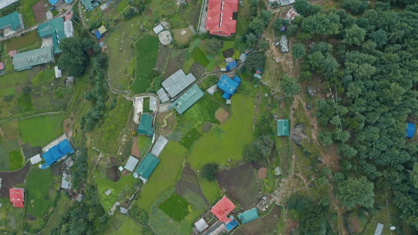 An aerial view of a rural landscape with scattered buildings surrounded green vegetation