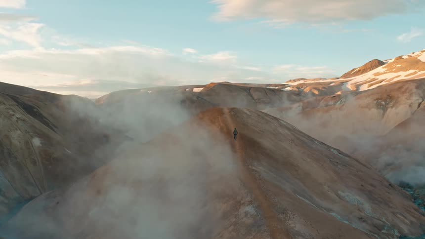 A person walks on a path at the top of a mountain