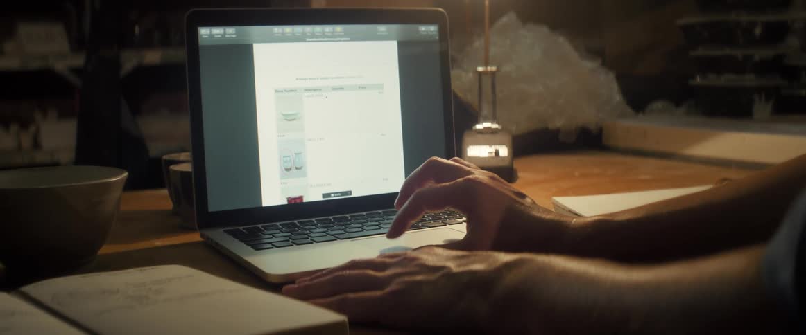 Hands typing on a laptop on a wooden table