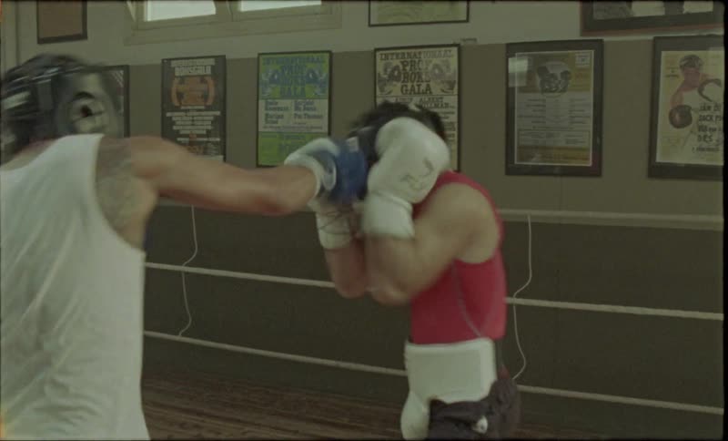 Two boxers inside the ring with boxing gloves and head gear sparring