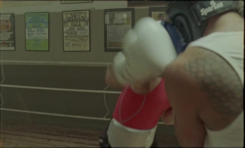 Two men training in a boxing gym with headgear and boxing gloves