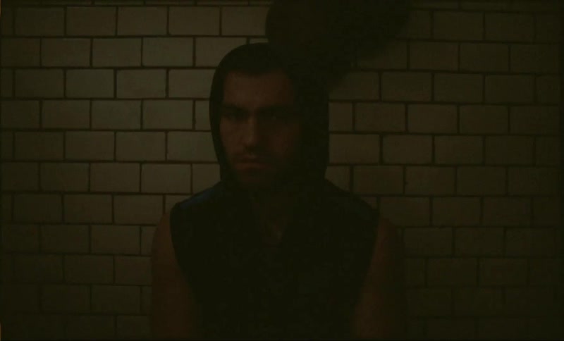 A man wearing a sleeveless hoodie in front of a wall