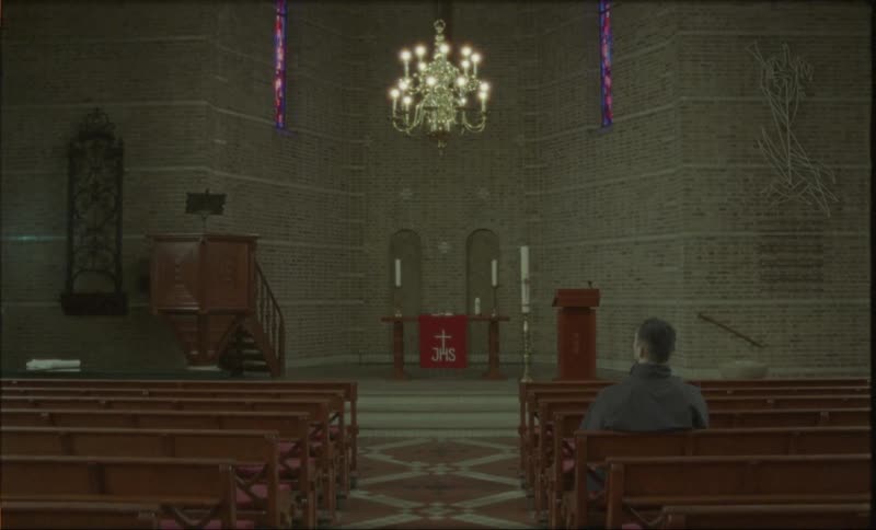 A man sits in a church pew while looking at the altar