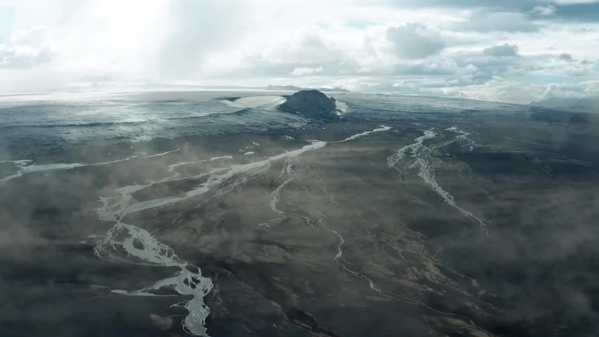 Aerial panorama of a black terrain with watermarks and a mountain in the background