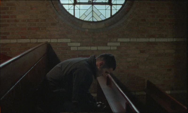 A man in deep thought seated in the pews of a church