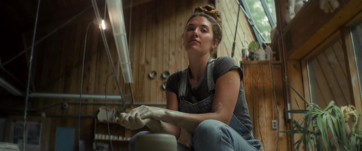 Young woman sitting with her hands dirty with clay