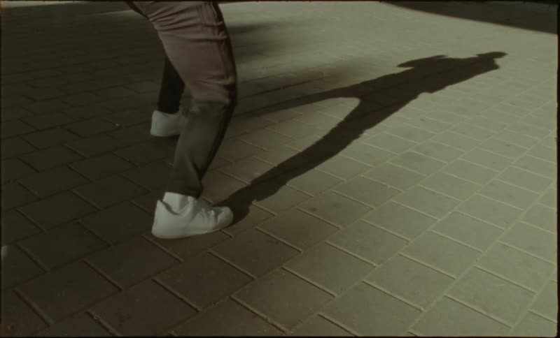 Closeup of a person casting a shadow on the ground while shadow boxing