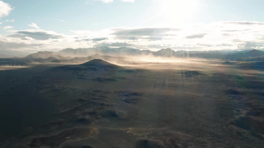 Aerial panorama of craters and mountains with sunlight reflections
