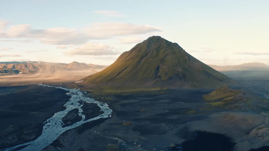 A large mountain next to a river and vast plain