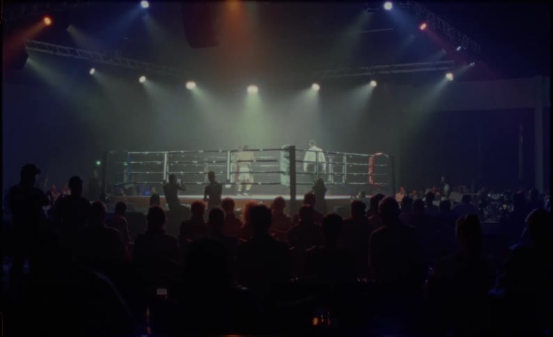 Boxers fighting in a ring and the crowd watching around