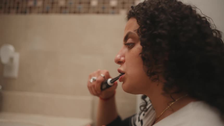 Woman brushes her teeth with a black toothbrush