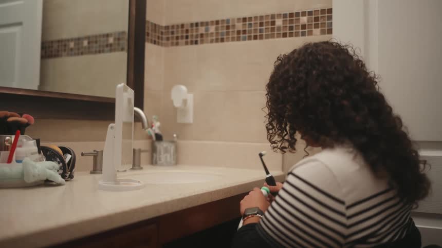Woman in a wheelchair in the bathroom brushing her teeth
