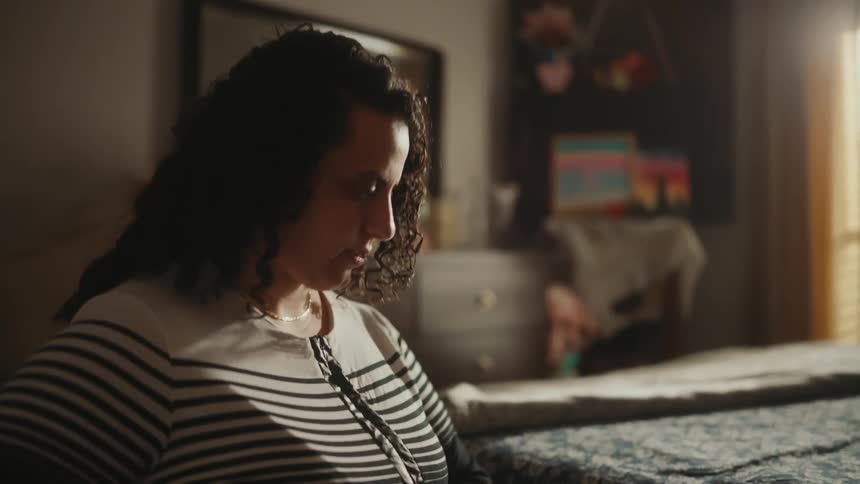 A mother helps her daughter to get out of the wheelchair in the bedroom