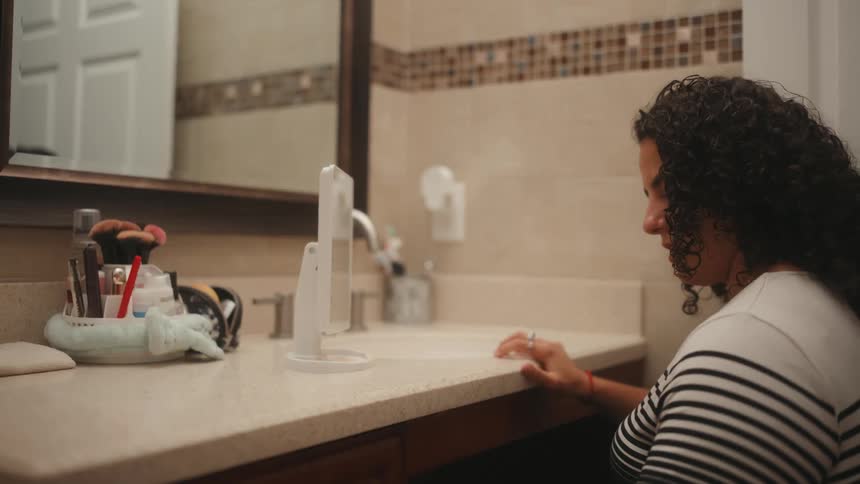Woman in a wheelchair entering the bathroom and picking up her toothbrush and toothpaste