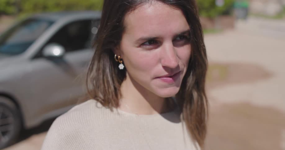 A clip of a lady smiling beside a car