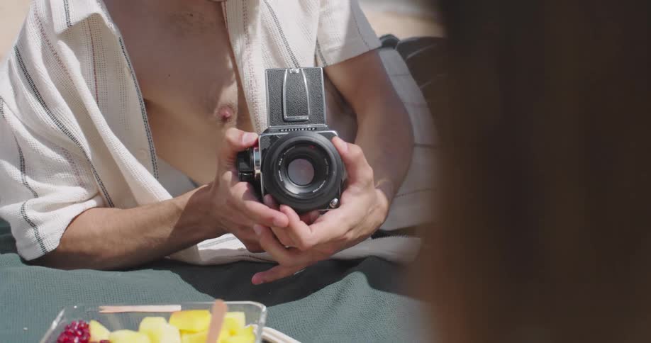 A man photographs a woman on a beach