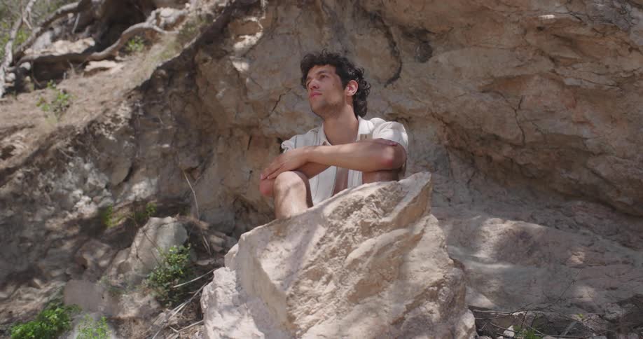 Man sitting on a rock on a hill in a natural tropical environment