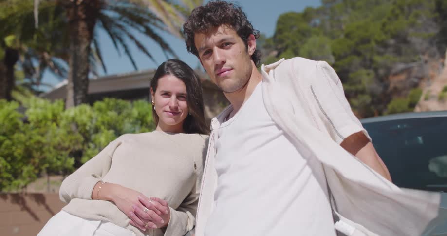 A man and woman leaning against a car outdoors