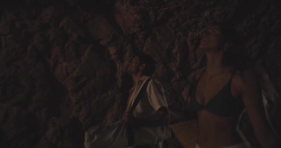 A young happy couple walking out of a cave into sunlight