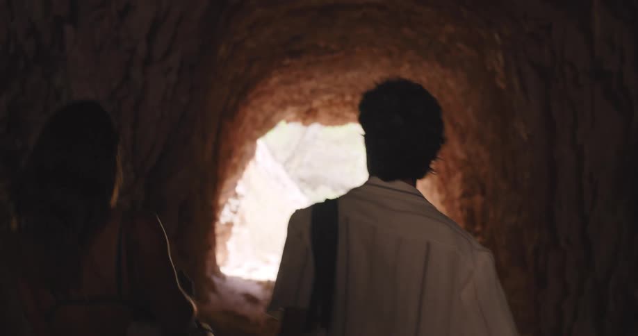 Couple walking through a tunnel towards the beach