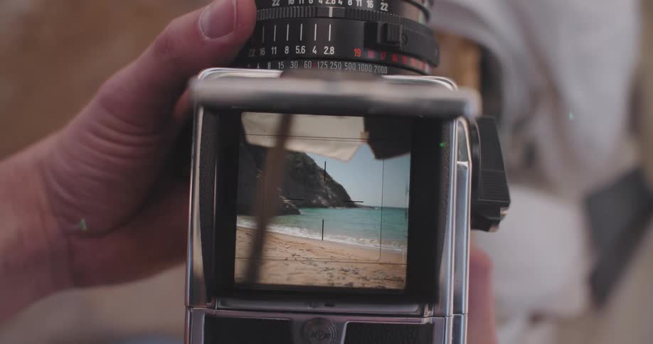 Person setting up a vintage camera overlooking the beach