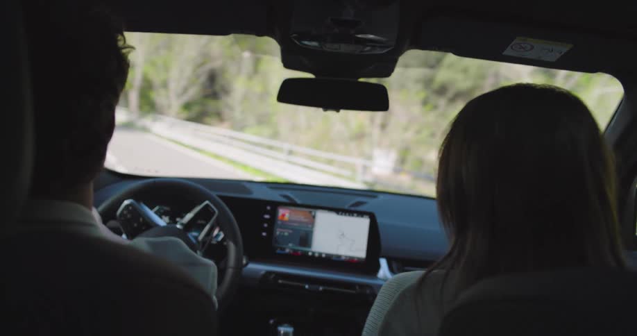 Man driving a bmw next to his wife on a paved road with nature around