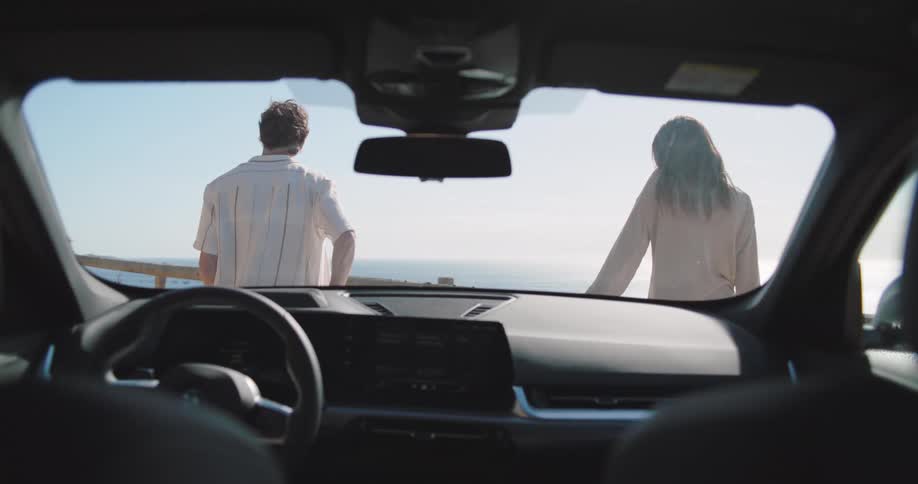 Couple standing in front of car looking out to the coast ahead