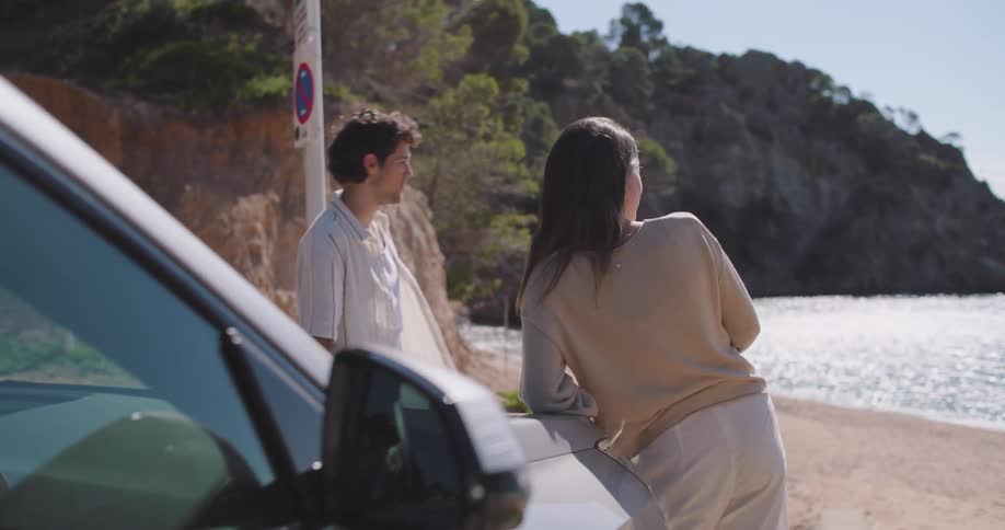 Couple walking out of parked car to admire the coast near the shoreline