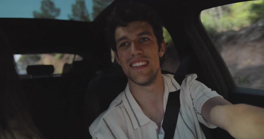 Couple driving along a road in a natural environment pointing fingers and talking