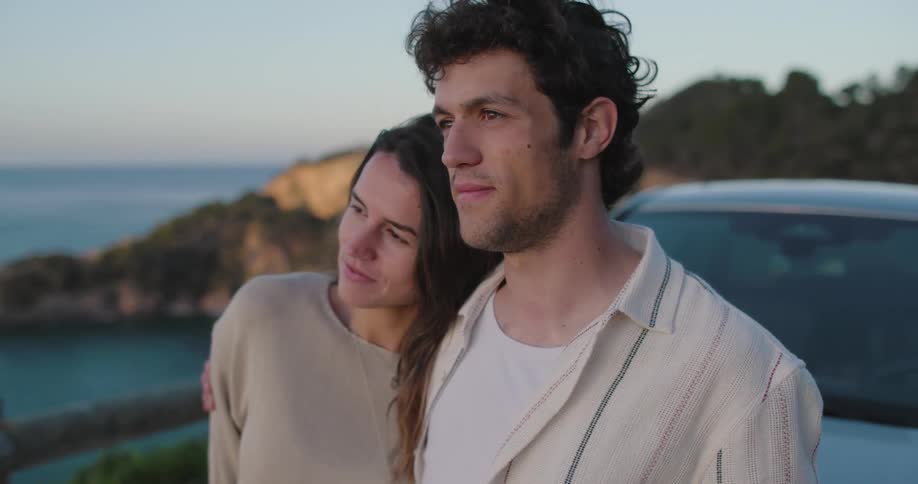 Portrait of a couple embracing in front of a car and enjoying a natural view