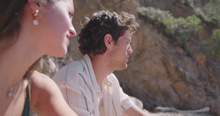 A man and a woman chat while sitting on a beach