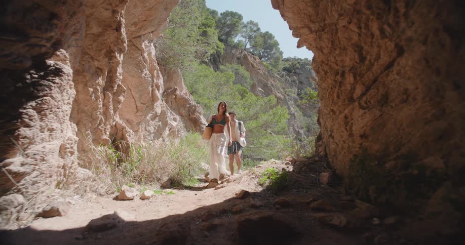 A couple walk into a cave in the mountains