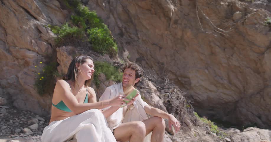 A man on a beach jogs over to a woman holding a book