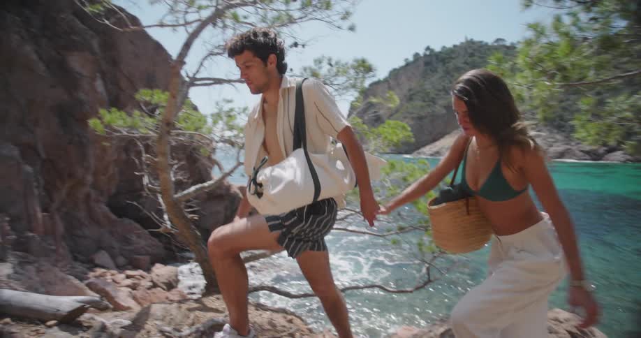 Couple hiking up a steep slope from the beach below