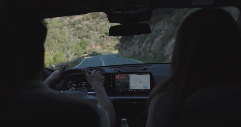 Interior view of a vehicle dashboard with a man driving and a woman next to him
