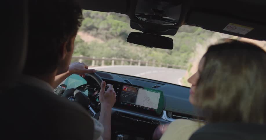 Couple inside the car driving along a paved road in a natural environment