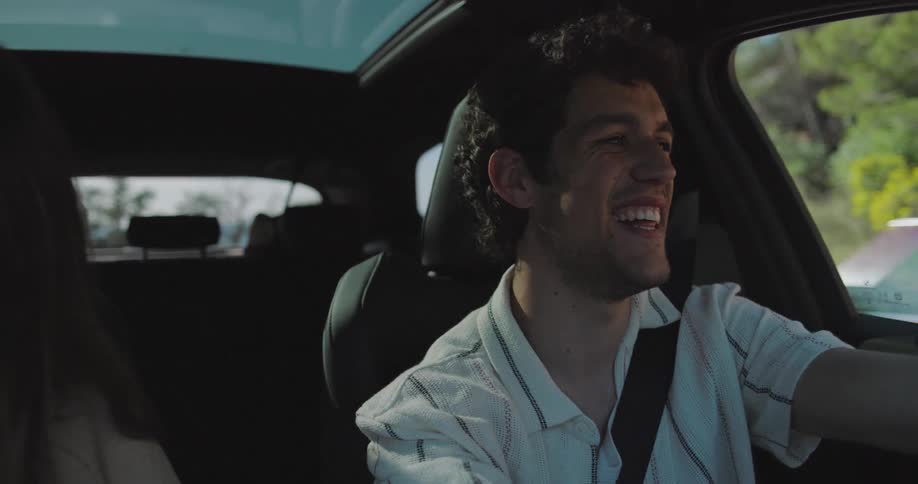 A man and a woman laugh while driving a car