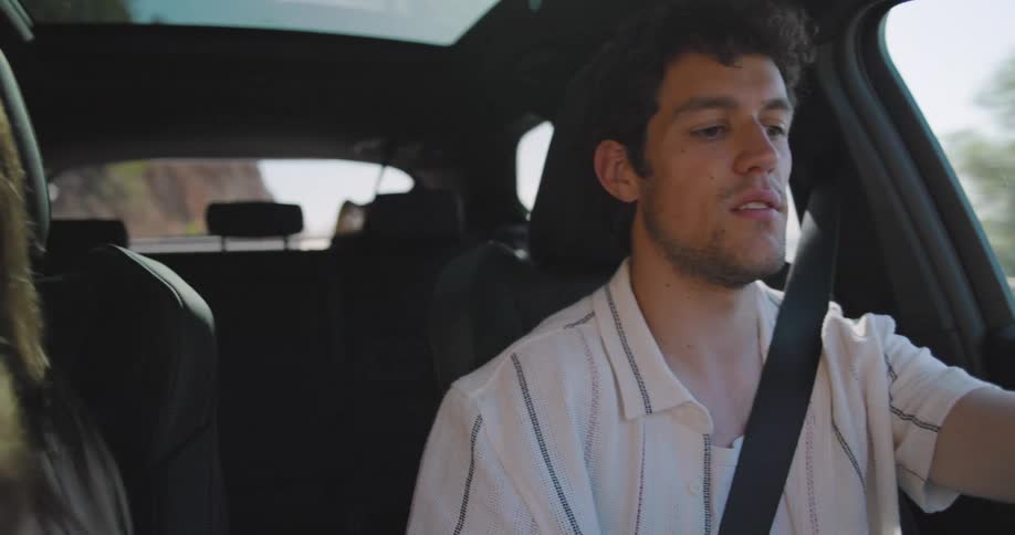 Woman putting on seat belt inside the car on the passenger and the man driving